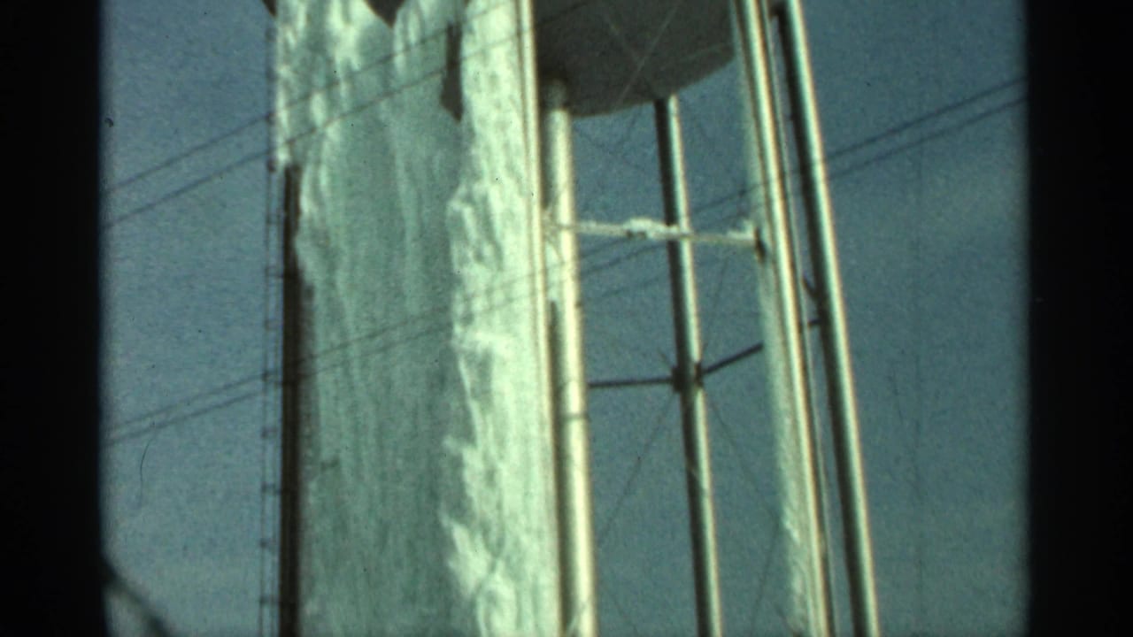Upper section of frozen water tank with lattice supports and sky.