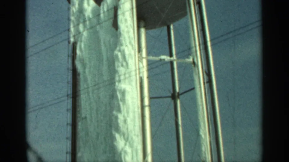1965 Duluth frame showing the upper portion of a frozen steel water tank and its support structure during an upward pan.
