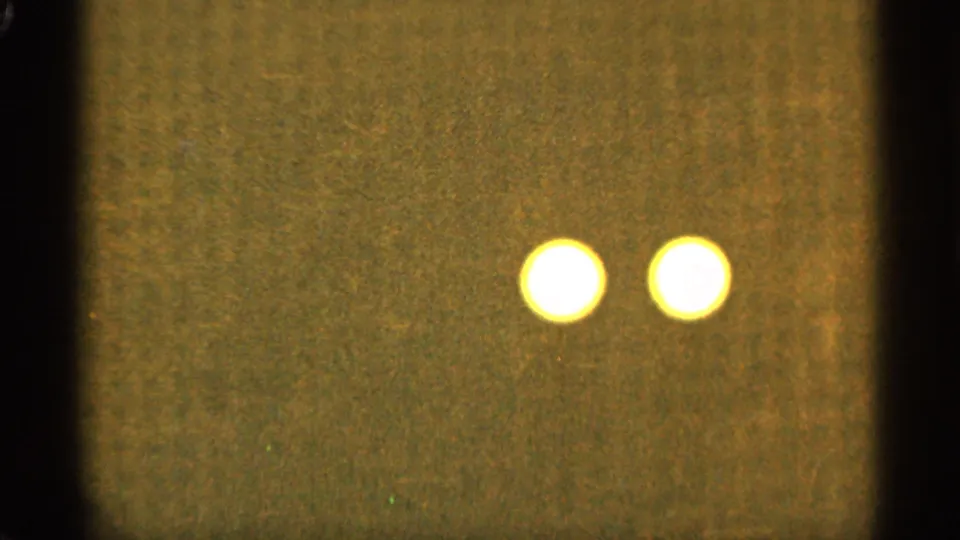Two out-of-focus yellow-white light orbs appear near the upper center of an abstract 8mm frame associated with Duluth, Minnesota in 1965.