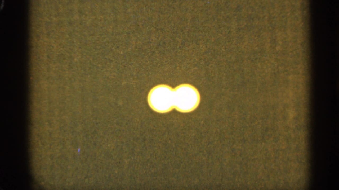Two overlapping bright orbs near the upper right on a dark grainy field.
