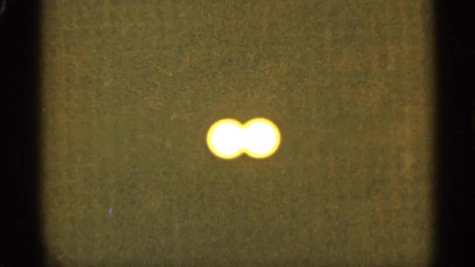 Two bright yellow-white light circles overlap slightly near the upper right of a soft, grainy 8mm frame from the 1965 Duluth-associated clip.