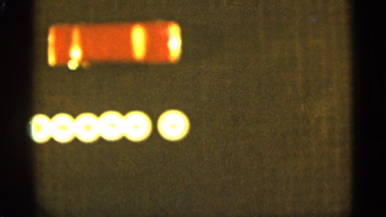 Yellow dot row and small red rectangular light on a dark screen.