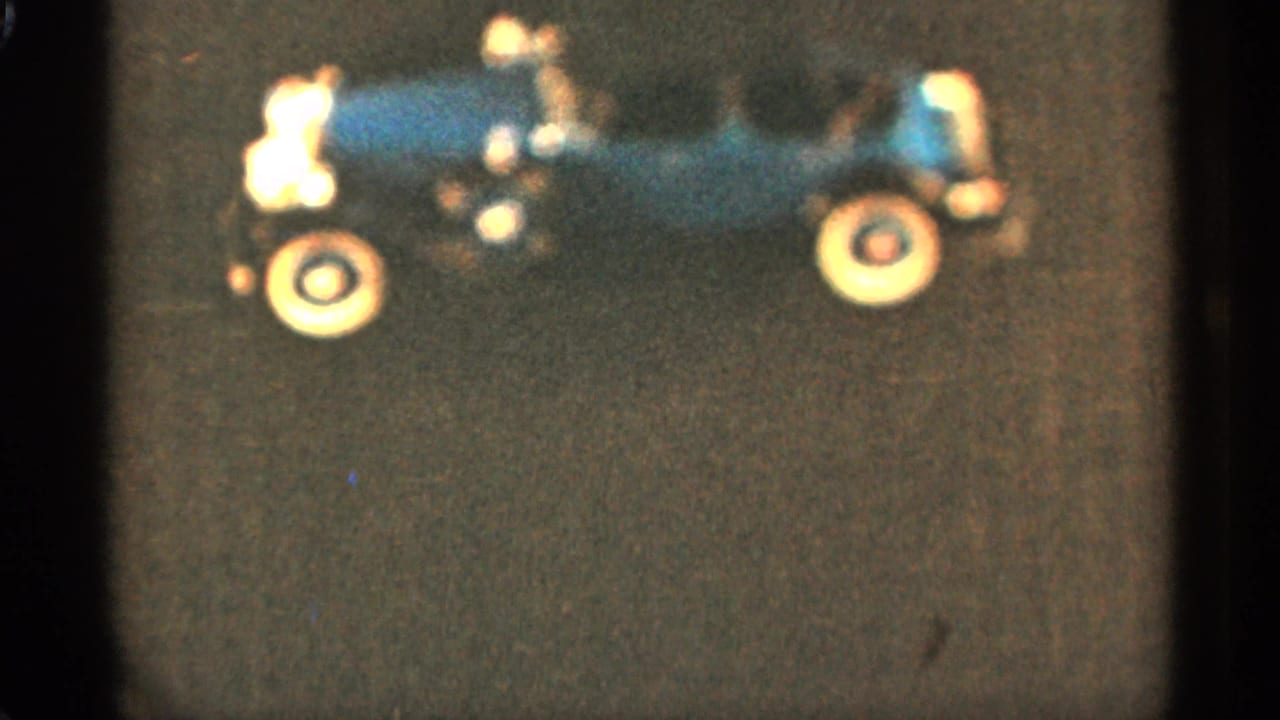 Blue toy car in side view with cream wheels against a dark background.
