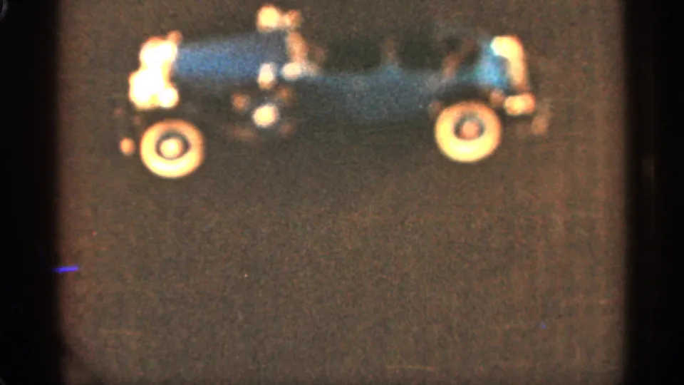 Soft 8mm frame from 1965 Duluth showing a close side view of the blue toy car on a dark surface.