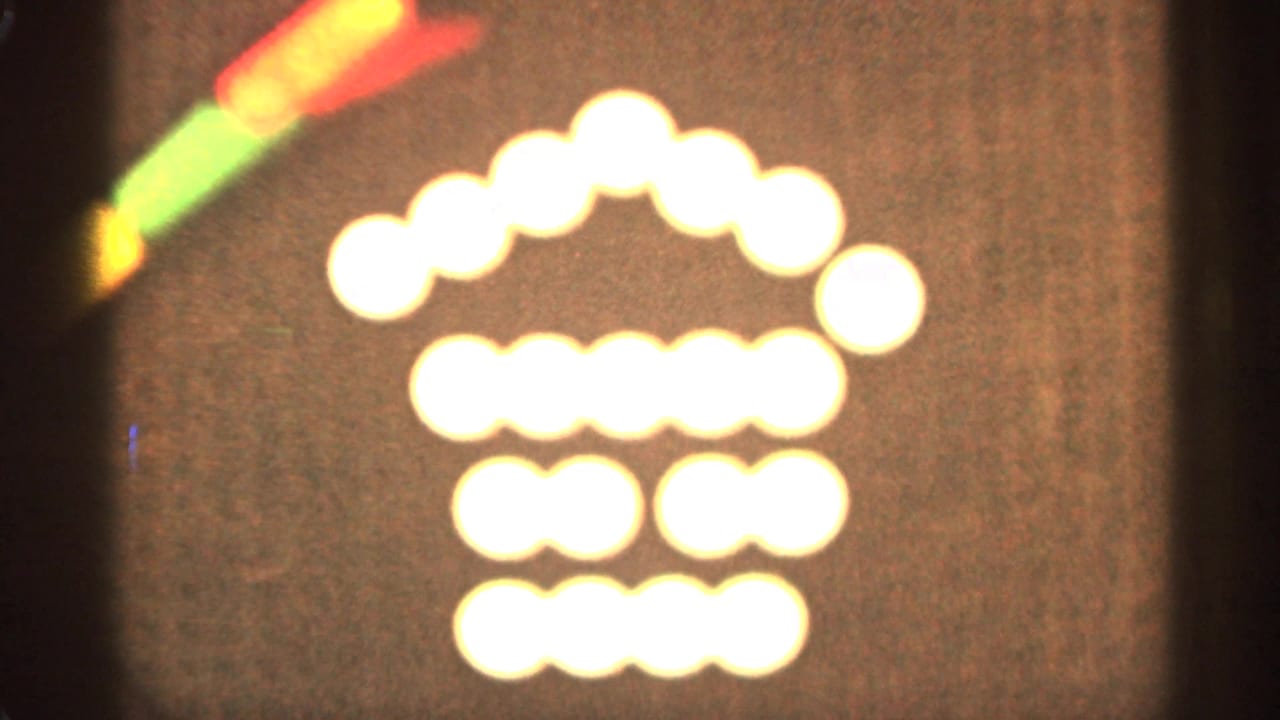 Soft glowing lights form a house-like shape on a dark background with a colored stick at the upper left.