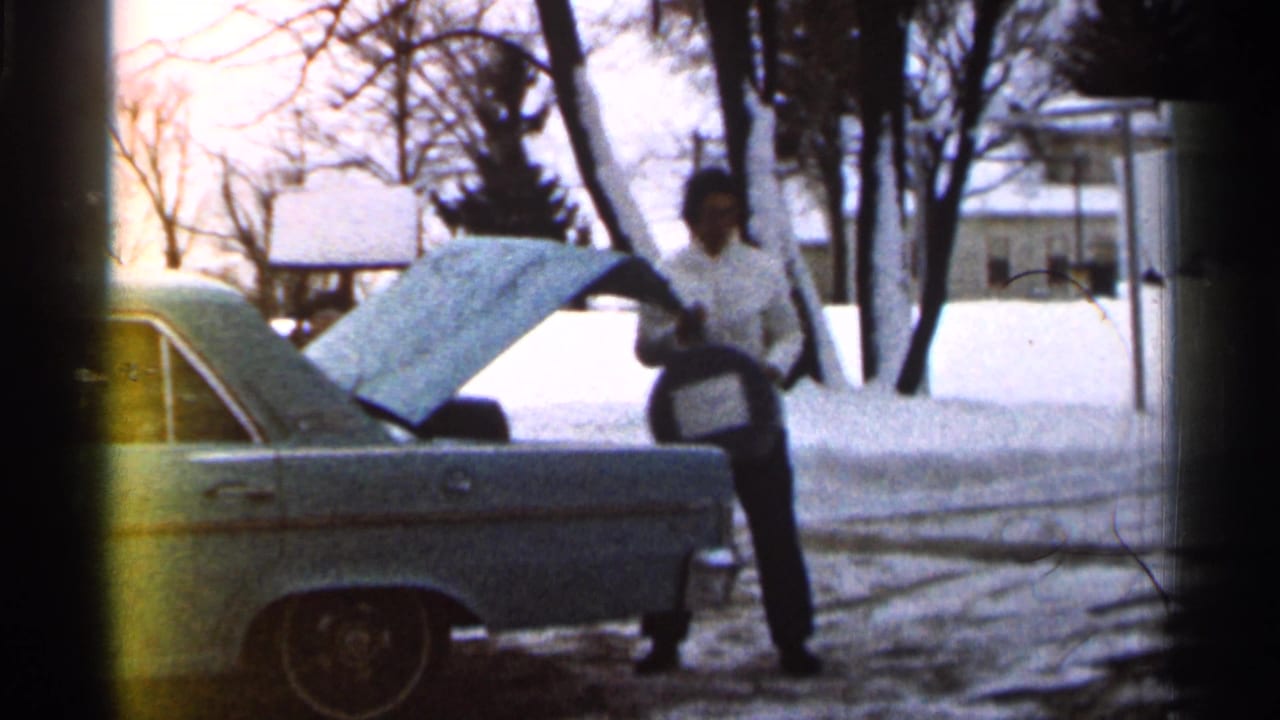 In Eau Claire, Wisconsin, 1966, a woman in a light coat stands by an open car trunk on a snowy residential street.