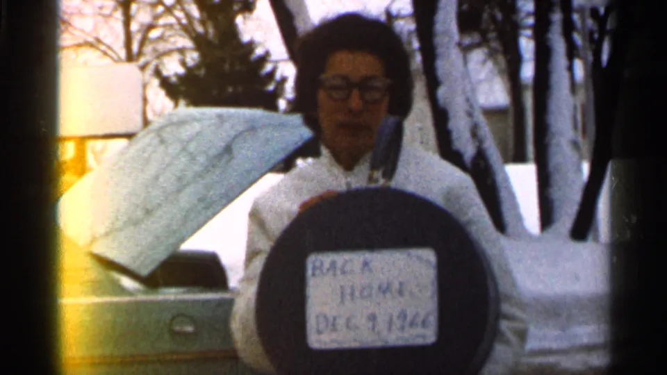The handwritten sign reading Back Home Dec 9 1966 is most legible as the woman stands by the snowy car in Eau Claire.