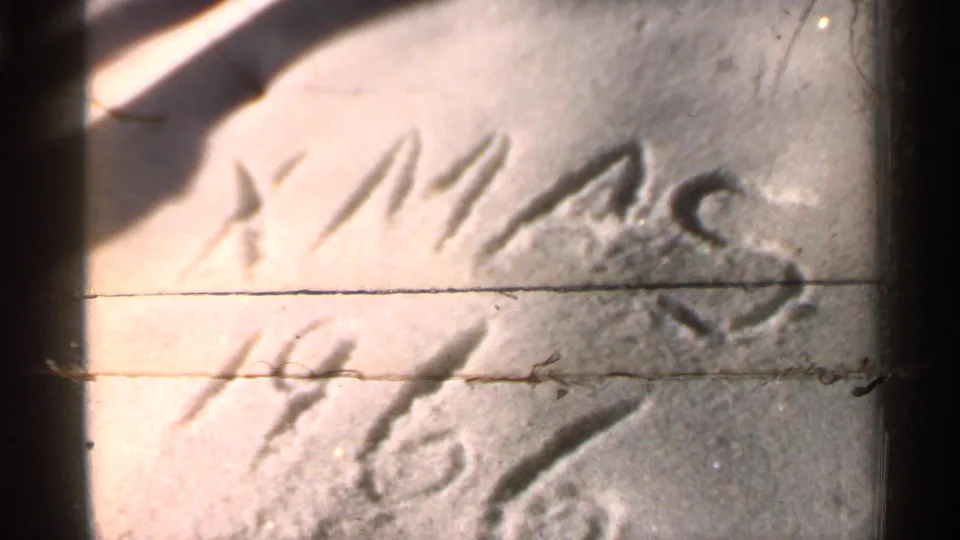 Close 8mm view of “XMAS 1966” scratched into snow, with dark frame edges and visible film wear.
