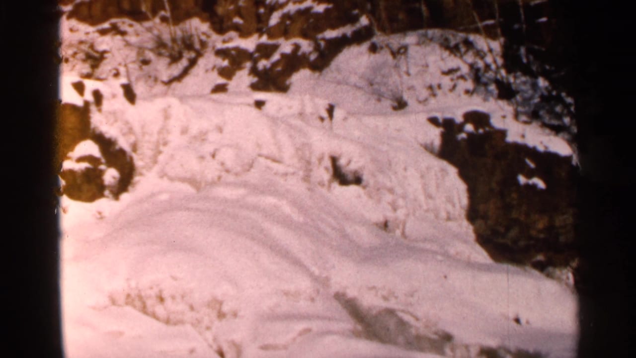 Snowy slope and rock outcrop with dark shadows along the right side.