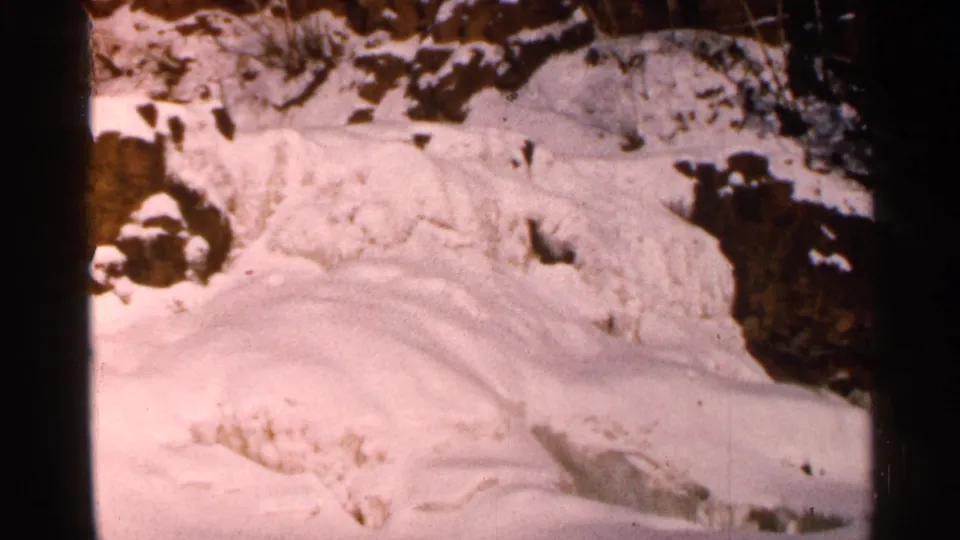 Final 8mm frame of the winter landscape shows snow, ice, exposed rock, and darkened edges suggesting exposure shift or the end of the shot.