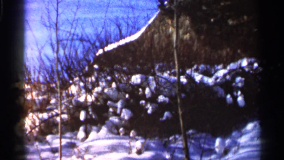 Brighter Eau Claire winter view from 1966 showing bare trees, blue sky, snow-covered ground, and a shadowed wooded edge.