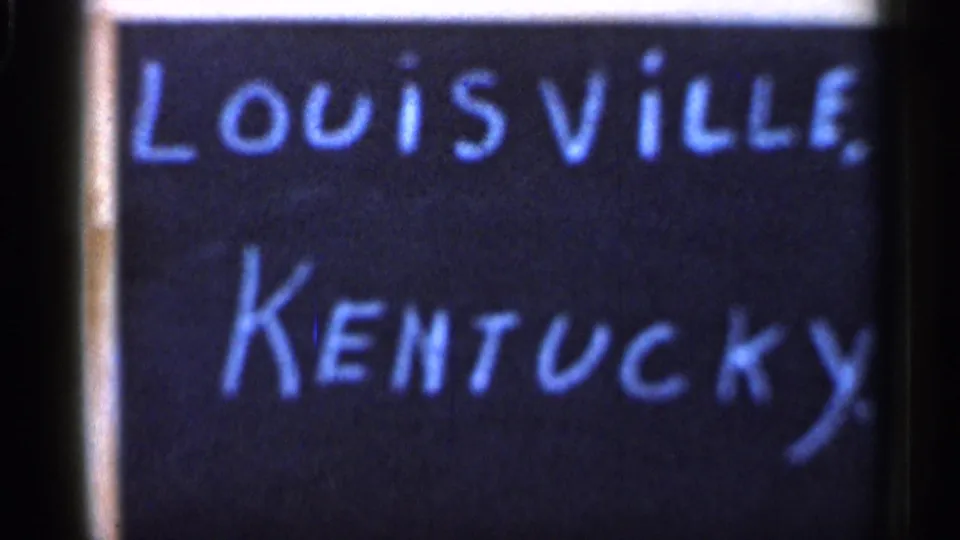 1966 8mm travel-marker frame showing a chalkboard labeled Louisville, Kentucky in blue chalk.
