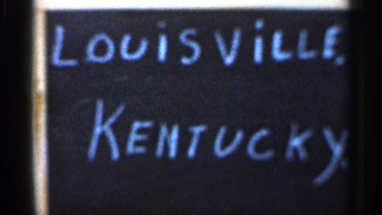 1966 8mm frame with a handwritten Louisville, Kentucky title card next to a soft, partially visible Christmas tree street scene.