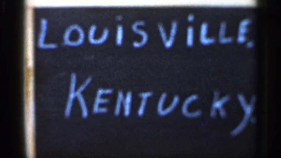 1966 8mm frame with a handwritten Louisville, Kentucky title card next to a soft, partially visible Christmas tree street scene.