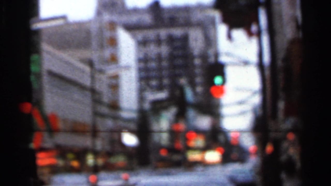 Blurred street scene with green and red traffic lights and car headlights.