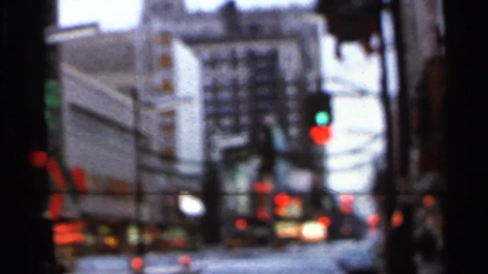 Low-light 8mm street view with traffic signals and building fronts, likely part of the Knoxville sequence identified by the title card.