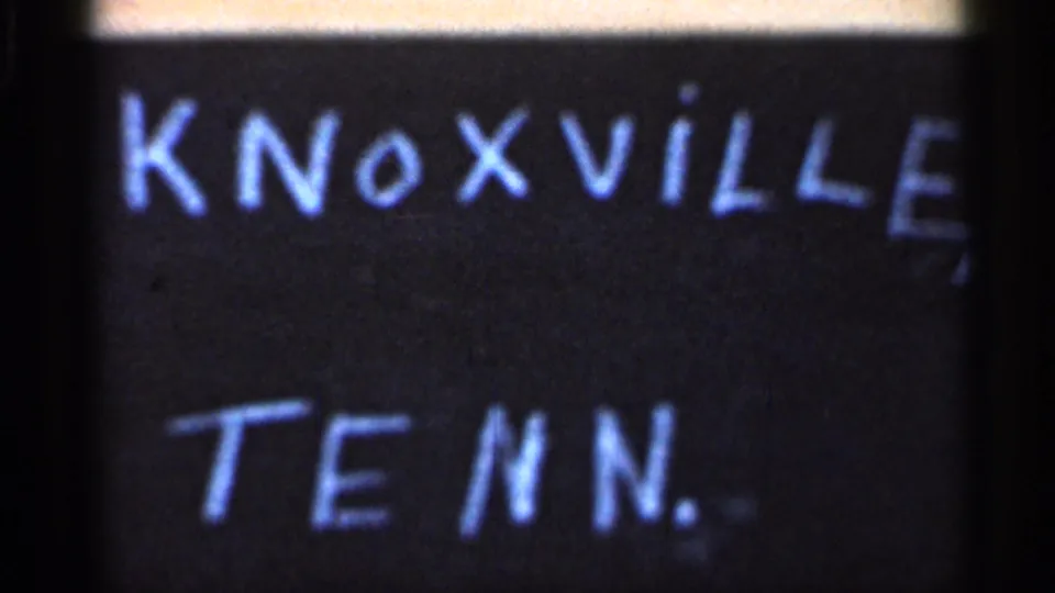 Close view of the handwritten Knoxville, Tenn. card with a soft urban street scene visible across the top of the frame.