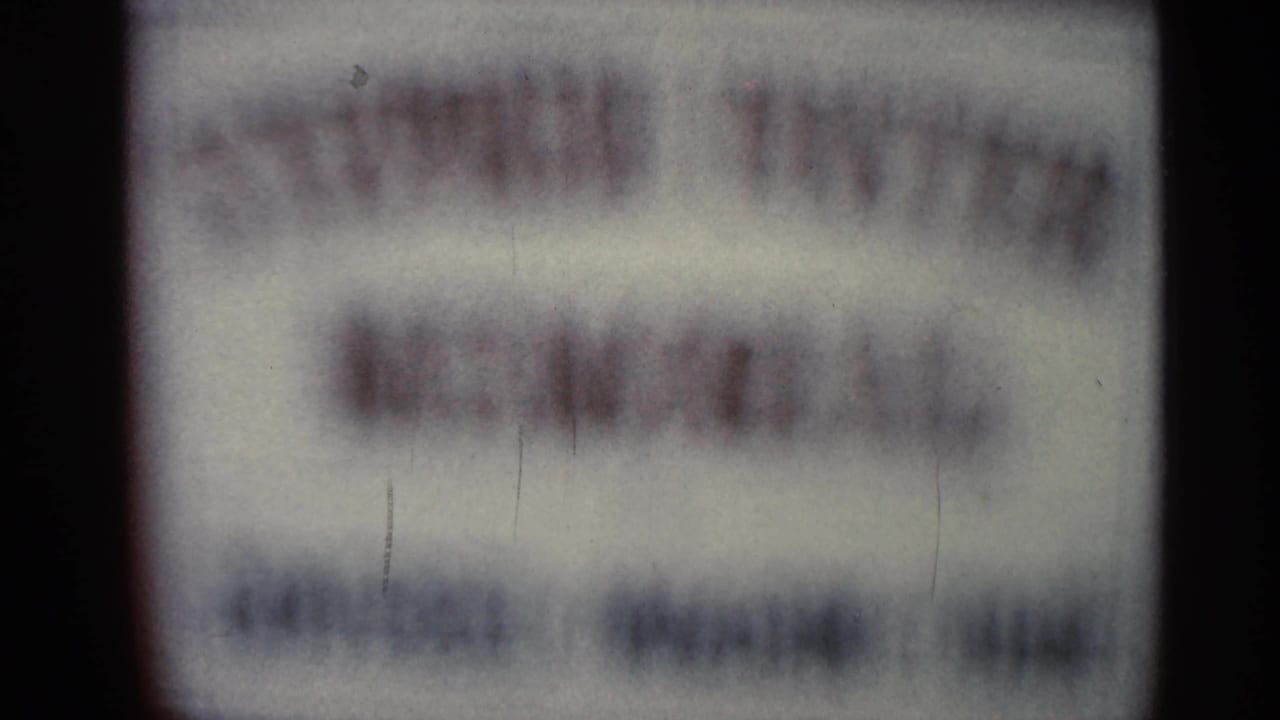 Blurred sign with red and dark lettering, unreadable due to soft focus.