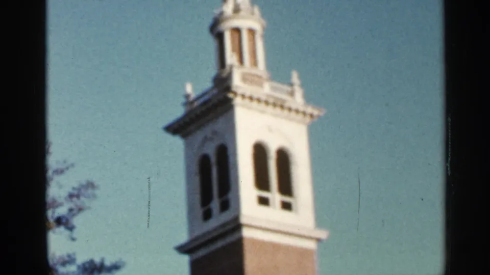 1966 Florida 8mm frame showing the tower from below, with arched windows, white trim, brickwork, and faint tree edges.