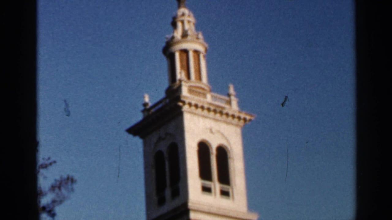 White tower or cupola against blue sky with film gate edges visible.