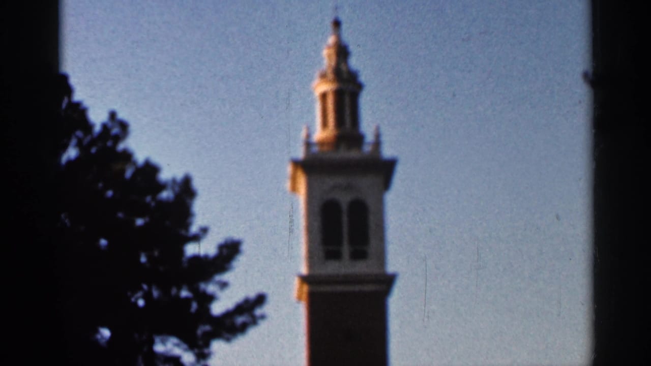 1966 Florida home-movie frame with the same tall tower, dark surrounding tree shapes, and visible 8mm frame borders.