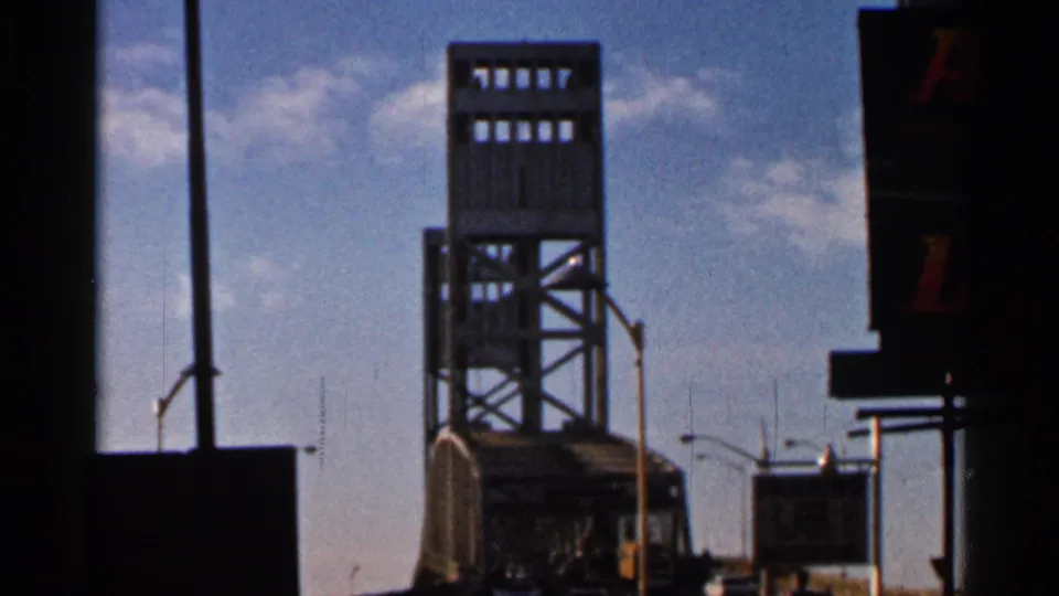 1966 Florida frame with the John Alsop Jr. Bridge tower, roadway signs, lamp posts, and dark window or vehicle framing.