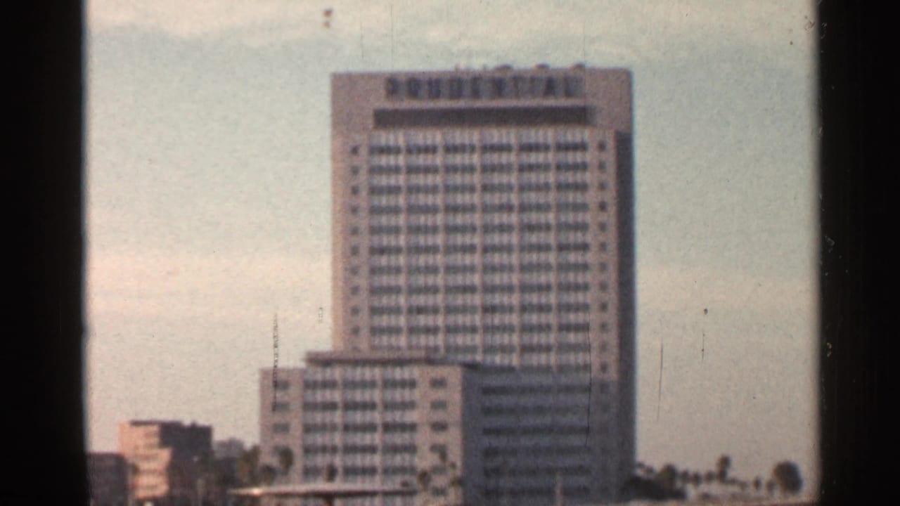 Tall high-rise building with a grid facade under a pale sky.