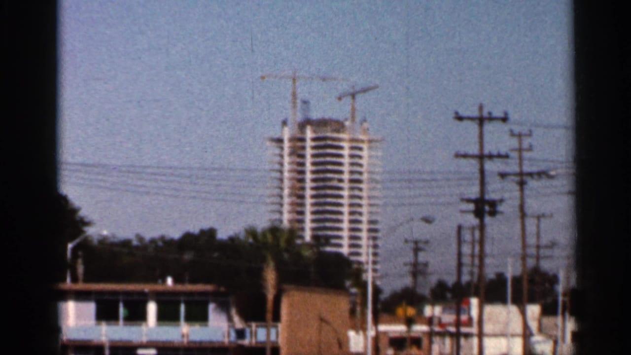 High-rise building under construction behind utility poles and low buildings.
