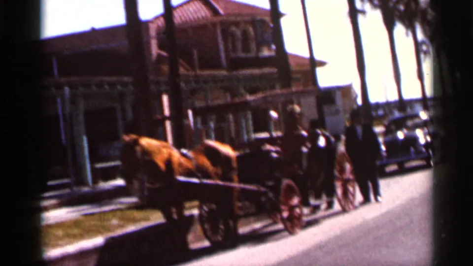1966 Florida street scene with a horse-drawn carriage, pedestrians, parked cars, palm trees, and a historic-looking building.