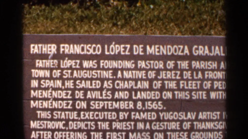 1966 visitor-shot frame of the Mission of Nombre de Dios plaque, with text about the priest statue and first Mass partly visible.