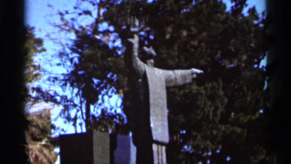 1966 Florida 8mm frame showing a robed priest statue with outstretched arms at Mission of Nombre de Dios.