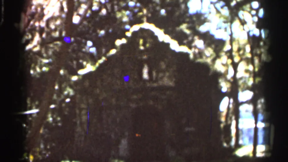 Final 1966 Florida frame showing the same rustic stone building among trees, with foliage, glare, and 8mm color texture.