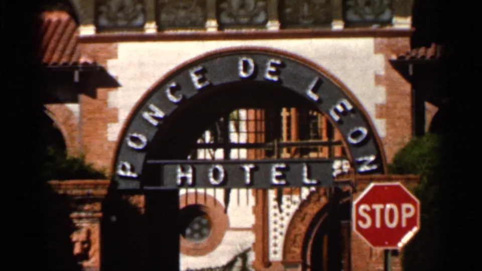 1966 Florida frame showing the arched Ponce de Leon Hotel entrance sign, stucco wall, tile roof detail, and roadside stop sign.