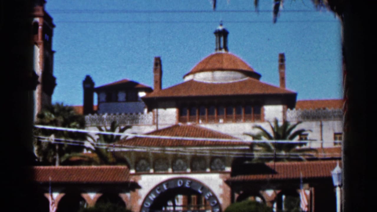 1966 Florida 8mm view of the Ponce de Leon Hotel entrance, showing red tile roofs, a dome, palms, and partial arched lettering.