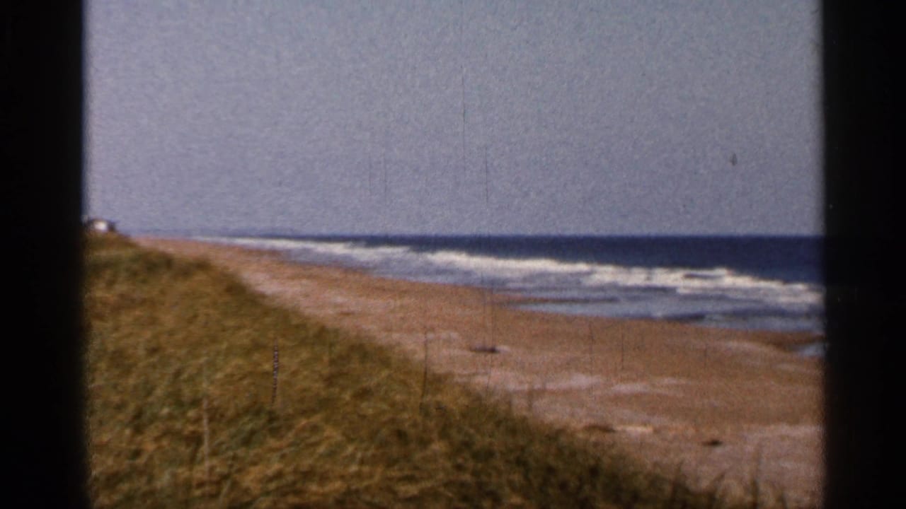 Florida beach with dunes, surf, sand, and dark film-frame borders.