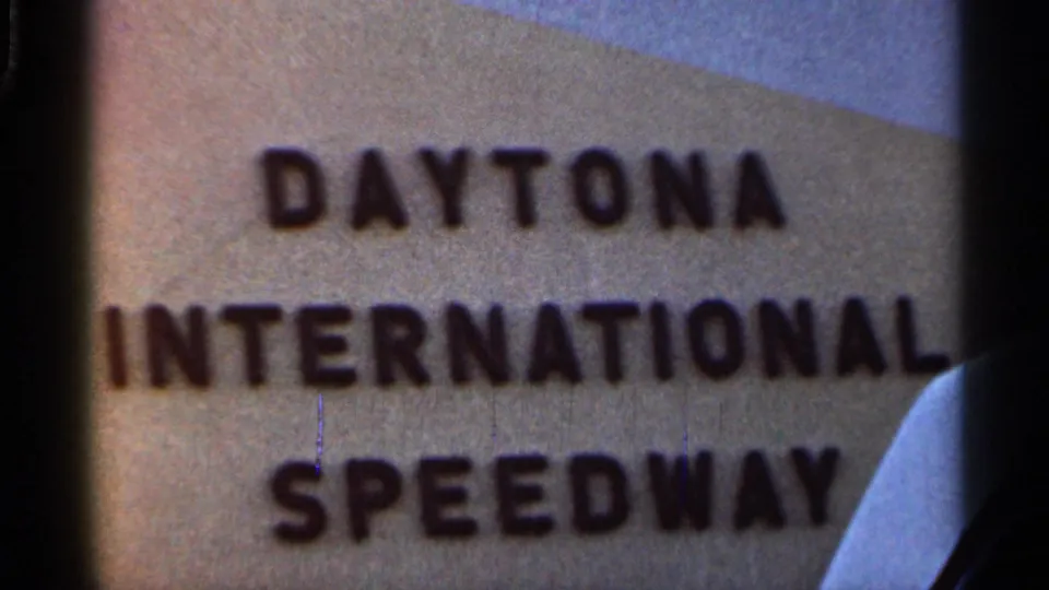 1966 8mm close-up of a sign with the words Daytona International Speedway, partially cropped within the film frame.