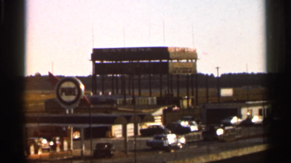 1966 Florida 8mm wide shot showing a speedway grandstand beyond a Pure Oil station and several period cars.