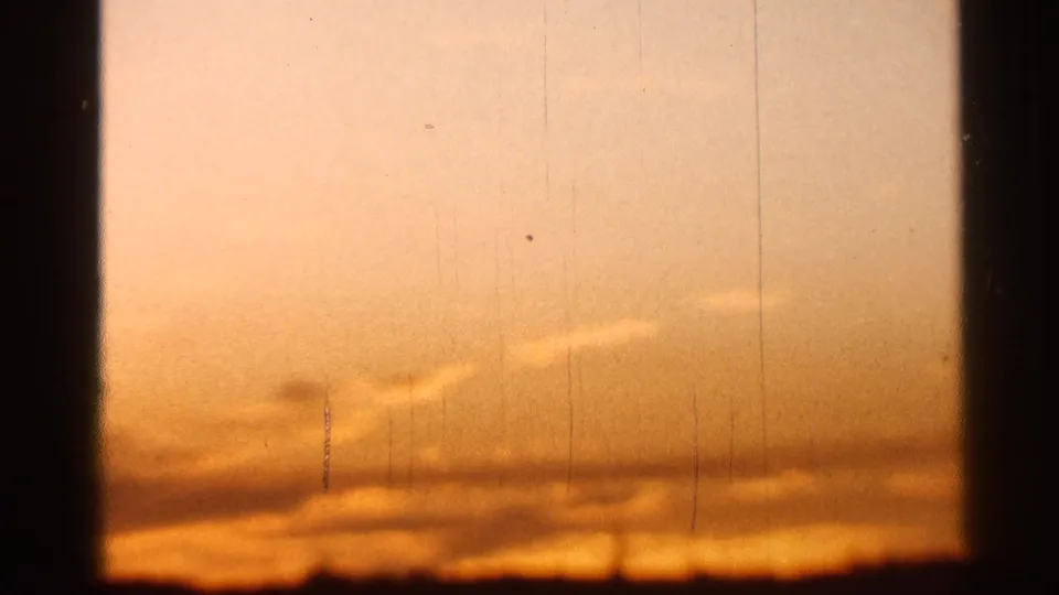 1966 Florida 8mm sunset view with orange haze, low cloud bands, dark horizon, and visible film wear.