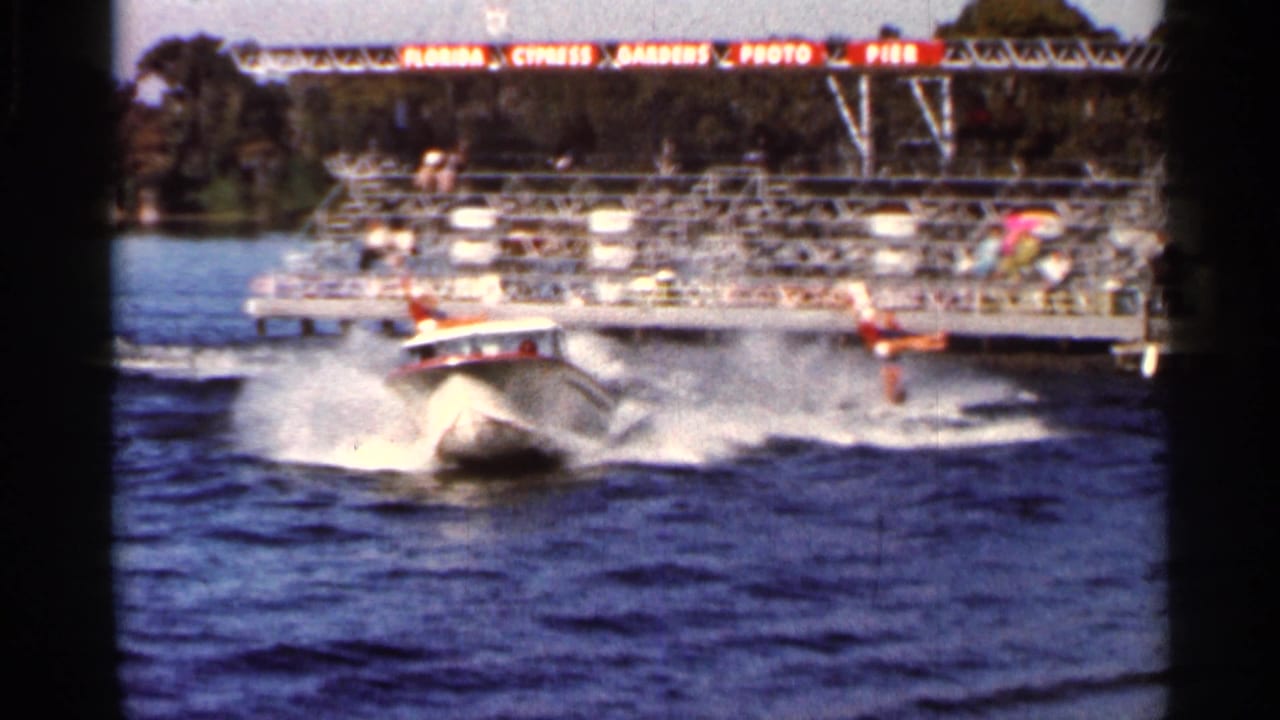 Speedboat and wake move past the Cypress Gardens photo pier in a 1966 Florida water-ski show scene.
