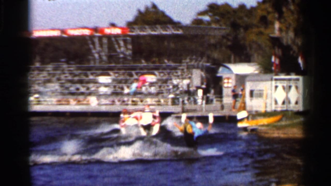 A speedboat pulls a water skier near a dock with spectators in this 1966 Florida home-movie frame.