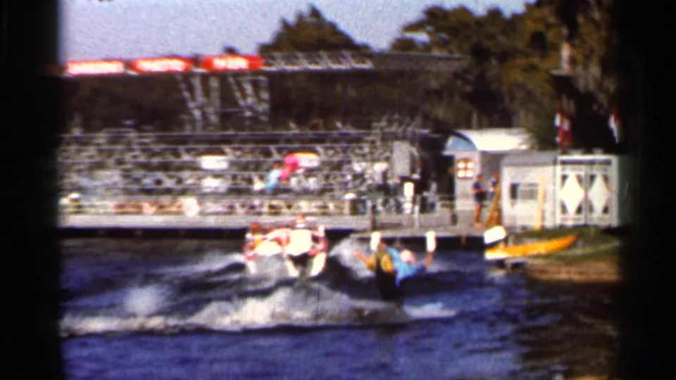 A speedboat pulls a water skier near a dock with spectators in this 1966 Florida home-movie frame.