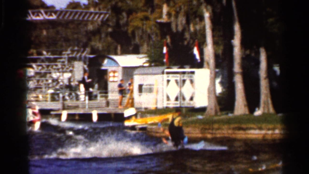 Water skier near a dock as a tow boat wake crosses a Florida lake.