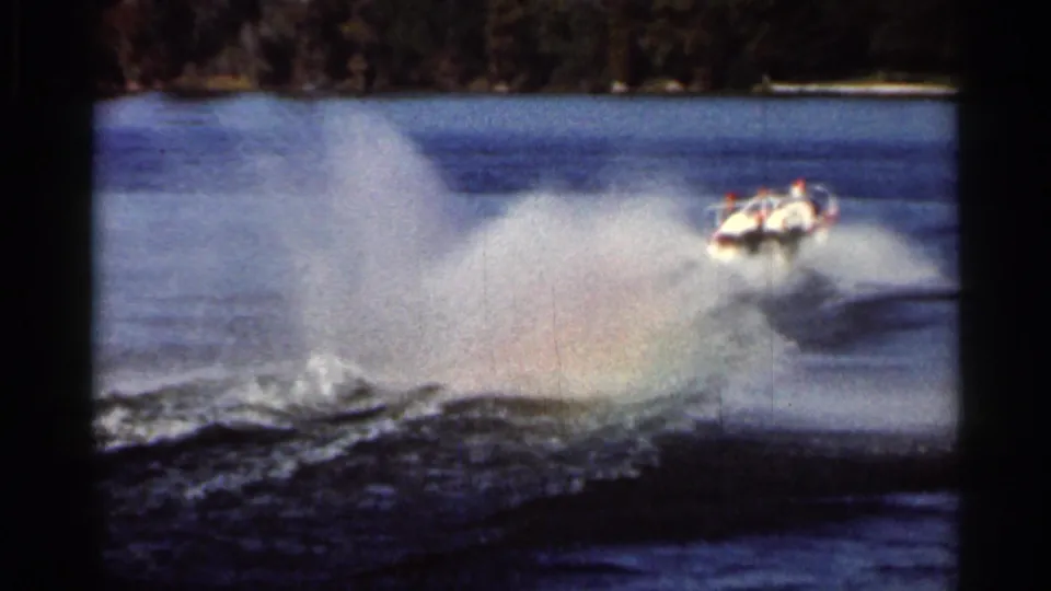 A small show boat turns sharply on a Florida lake, creating a large spray plume during the Cypress Gardens water ski show.