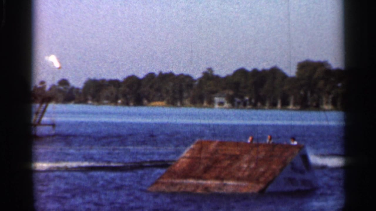 Water-sport ramp on a lake with tree-lined shore and dark film borders.
