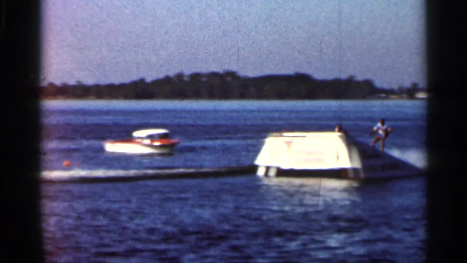 1966 Florida 8mm frame with a skier at right, a white boat, and a Cypress Lakes ramp on blue lake water.