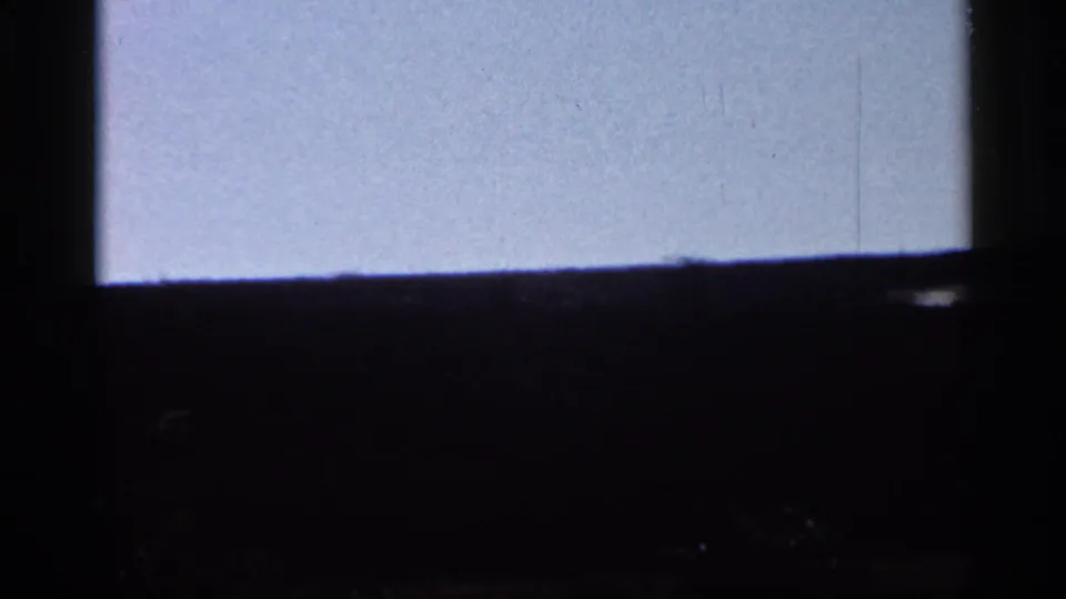 1966 Florida home-movie frame with a dark window frame dividing a pale sky and low wooded horizon, with the tower no longer clear.