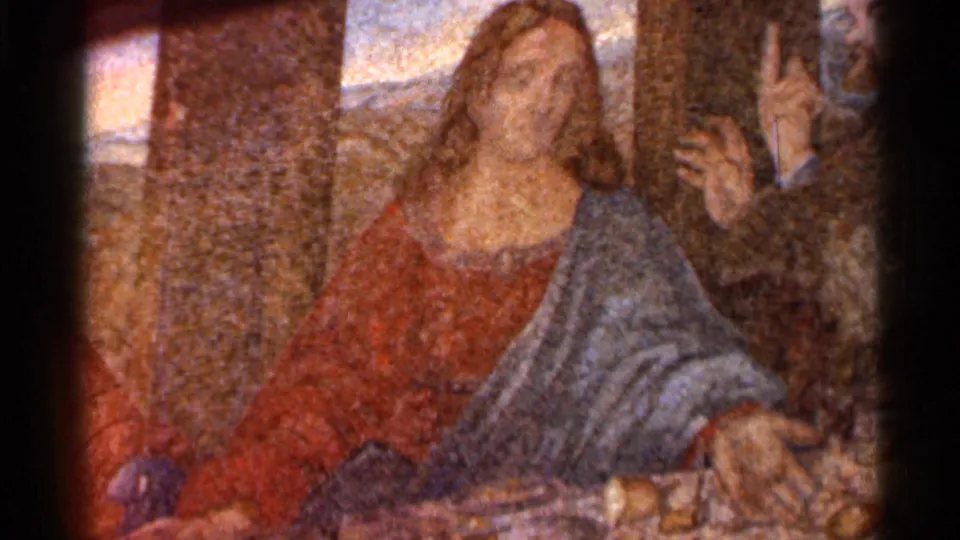 Close 8mm view of the central Jesus figure in a Last Supper reproduction, with disciples partly visible at the sides.