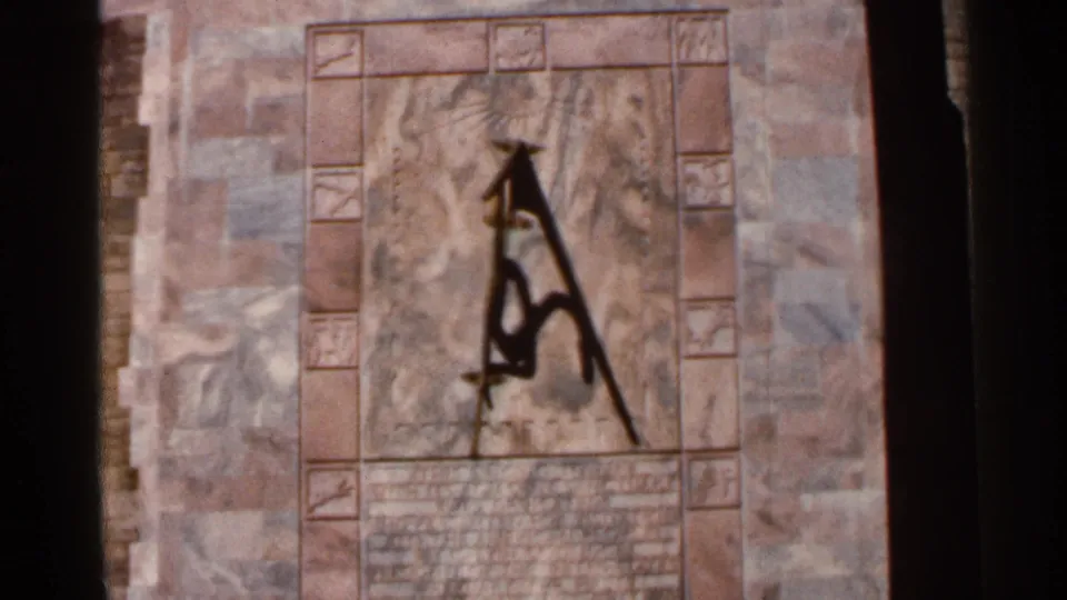 1966 Florida 8mm frame of a dark abstract mark on a decorative stone surface, framed tightly in bright outdoor light.