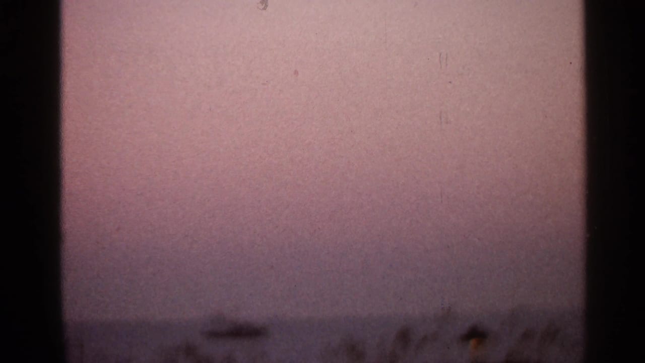 Pink hazy sky above a dark low horizon with 8mm frame edges visible.