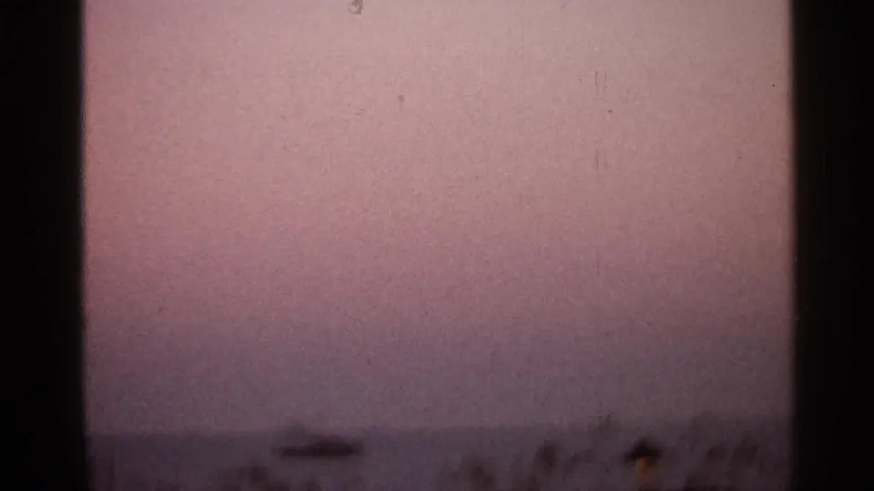 1966 8mm home-movie frame from Florida metadata showing a soft pink dusk sky over a dark, indistinct horizon.